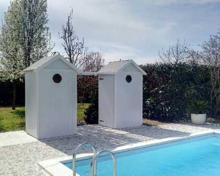 2 Cabina spogliatoio gemelle colore bianco posizionayte a bordo di una azzurra piscina, sulla parete un oblò rotondo per l'areazione