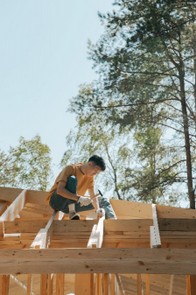 montatore casette in legno durante il montaggio di un tetto con chiodi e martello 