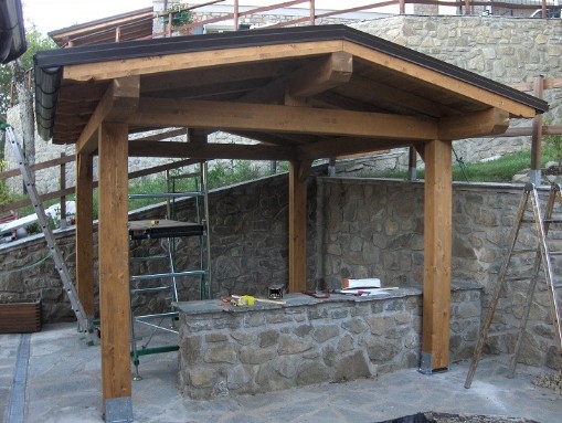 tettoia in legno massiaccia a due acque, costruita tra due muretti di recinzione in sasso